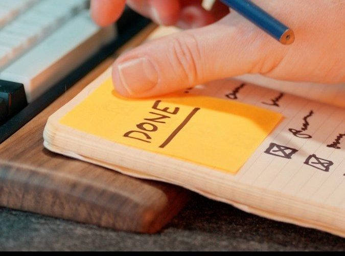 A hand writing "done" on a notepad